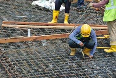 MALACCA, MALAYSIA -27 Mayıs 2016: Malezya 'daki inşaat alanında çelik takviye barı üreten inşaat işçileri. Destek çubuğu ince kabloyla birbirine bağlıydı..  