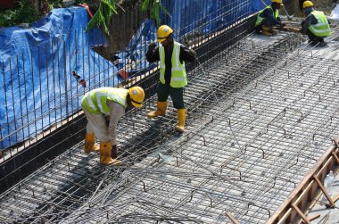 MALACCA, MALAYSIA -27 Mayıs 2016: Malezya 'daki inşaat alanında çelik takviye barı üreten inşaat işçileri. Destek çubuğu ince kabloyla birbirine bağlıydı..  