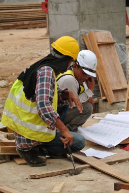 MALACCA, MALAYSIA - 4 Mayıs 2016: İnşaat işçileri inşaat alanlarında inşaat çizimlerini tartışıyor ve tutuyorlar.