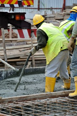 SELANGOR, MALAYSIA - 18 HAZİRAN 2016, İnşaat işçileri inşaat alanında beton vibratör kullanarak inşaat çalışmalarına dökülen beton çamuru sıkıştırdılar.. 