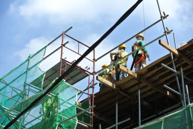 MELAKA, MALAYSIA -6 Nisan 2016: Melaka, Malezya 'daki inşaat sahasında çalışırken emniyet kemeri ve yeterli güvenlik donanımı takan inşaat işçileri.