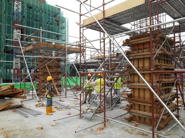 MALACCA, MALAYSIA -JUNE 18, 2016: Construction workers fabricating column timber form work and reinforcement bar at the construction site in Malacca, Malaysia. 