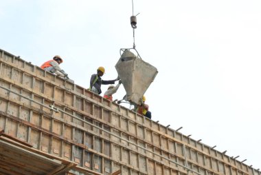 JOHOR, MALAYSIA - MAYIS 06, 2016: İnşaat alanındaki sütun biçimindeki çalışmalara beton kova döken bir grup inşaat işçisi.  