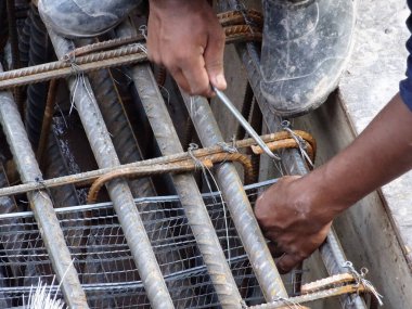 KUALA LUMPUR, MALAYSIA -16 Ekim 2017: İnşaat işçileri inşaat alanında çelik takviye çubuğu üretiyorlar. Destek çubuğu ince kablolar kullanılarak birbirine bağlanmış.