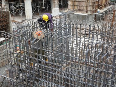 KUALA LUMPUR, MALAYSIA -16 Ekim 2017: İnşaat işçileri inşaat alanında çelik takviye çubuğu üretiyorlar. Destek çubuğu ince kablolar kullanılarak birbirine bağlanmış.