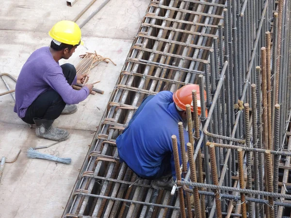 KUALA LUMPUR, MALAYSIA -16 Ekim 2017: İnşaat işçileri inşaat alanında çelik takviye çubuğu üretiyorlar. Destek çubuğu ince kablolar kullanılarak birbirine bağlanmış.