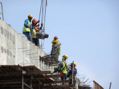 KUALA LUMPUR, MALAYSIA - MAYIS 05, 2016: İskeleye tırmanırken emniyet kemeri ve yeterli güvenlik teçhizatı takan inşaat işçileri. Bu, yüksek seviyede çalışırken güvenliklerini sağlamak için.. 