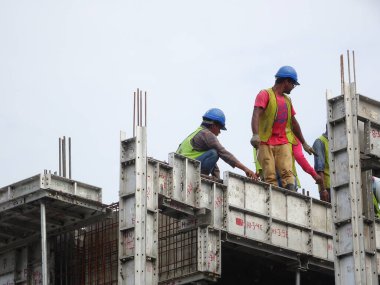 KUALA LUMPUR, MALAYSIA - MAYIS 05, 2016: İskeleye tırmanırken emniyet kemeri ve yeterli güvenlik teçhizatı takan inşaat işçileri. Bu, yüksek seviyede çalışırken güvenliklerini sağlamak için.. 