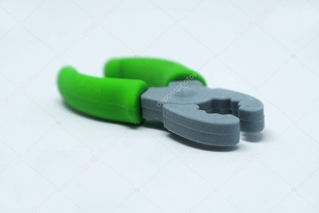 Selected focused of green toy pliers made from soft rubber isolated on white background. 