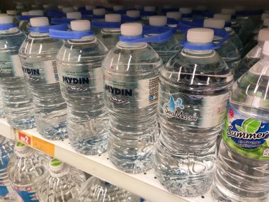 KUALA LUMPUR, MALAYSIA -15 Nisan 2020: İçme suyu paketlenir ve plastik şişelerde çeşitli markalarla etiketlenir. Süpermarketin içindeki bir rafta gösteriliyor.