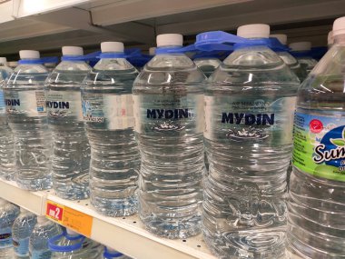 KUALA LUMPUR, MALAYSIA -15 Nisan 2020: İçme suyu paketlenir ve plastik şişelerde çeşitli markalarla etiketlenir. Süpermarketin içindeki bir rafta gösteriliyor.