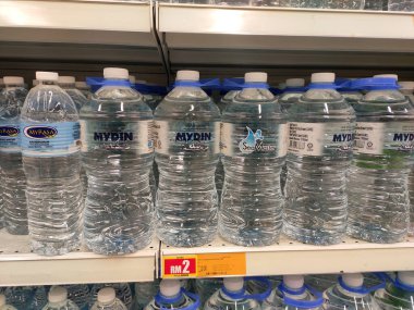 KUALA LUMPUR, MALAYSIA -15 Nisan 2020: İçme suyu paketlenir ve plastik şişelerde çeşitli markalarla etiketlenir. Süpermarketin içindeki bir rafta gösteriliyor.
