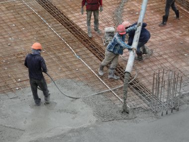 KUALA LUMPUR, MALAYSIA - 16 Haziran 2017: İnşaat işçileri inşaat sahasındaki beton pompalama makinesinin beton örümcek hortumunu kullanarak beton beton döşeyen inşaat işçileri.  