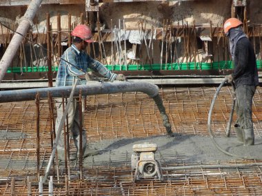 KUALA LUMPUR, MALAYSIA - 16 Haziran 2017: İnşaat işçileri inşaat sahasındaki beton pompalama makinesinin beton örümcek hortumunu kullanarak beton beton döşeyen inşaat işçileri.  