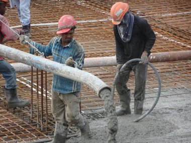 KUALA LUMPUR, MALAYSIA - 16 Haziran 2017: İnşaat işçileri inşaat sahasındaki beton pompalama makinesinin beton örümcek hortumunu kullanarak beton beton döşeyen inşaat işçileri.  