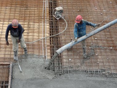 KUALA LUMPUR, MALAYSIA - 16 Haziran 2017: İnşaat işçileri inşaat sahasındaki beton pompalama makinesinin beton örümcek hortumunu kullanarak beton beton döşeyen inşaat işçileri.  