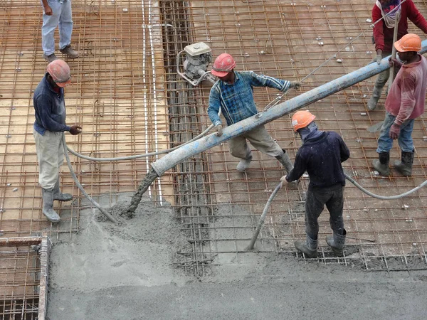 KUALA LUMPUR, MALAYSIA - 16 Haziran 2017: İnşaat işçileri inşaat sahasındaki beton pompalama makinesinin beton örümcek hortumunu kullanarak beton beton döşeyen inşaat işçileri.  