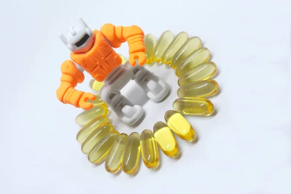 Fish oil capsules with orange toy robot made from rubber in the middle isolated on white background
