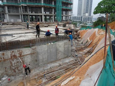 SEREMBAN, MALAYSIA - 30 Mart 2020: İnşaat işçileri inşaat alanında çelik takviye çubuğu üretiyorlar. Formatörleri kullanmadan önce küçük kabloları kullanarak birbirlerine bağladılar.. 