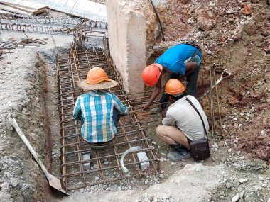 SEREMBAN, MALAYSIA - 30 Mart 2020: İnşaat işçileri inşaat alanında çelik takviye çubuğu üretiyorlar. Formatörleri kullanmadan önce küçük kabloları kullanarak birbirlerine bağladılar.. 