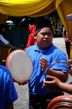 KUALA LUMPUR, MALAYSIA - 2 Mart 2019: Çocuk Malezya geleneksel düğün töreninde kompang oynuyor. Onlar kompang çalarken birlikte şarkılar söyleyecekler. Kompang geleneksel Malezya davuludur.. 