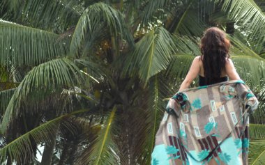 Palmiye ağacına bakan genç bir kadının arka görüntüsü. Denize ve dikiz aynasına bakan genç bir kadının portresi