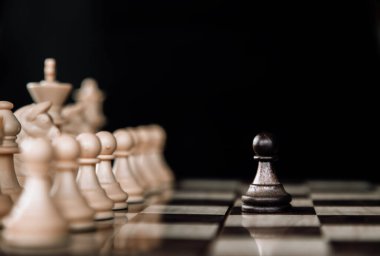 Satranç tahtası arkaplanına satranç taşı. Merkez piyon odaklanmış durumda. Takım çalışması konsepti.