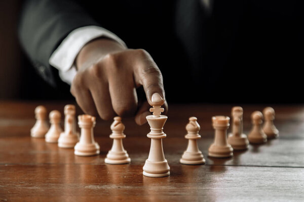 Рука бизнесмена, движущегося шахматной фигурой в игре успеха соревнования. стратегия, тонизированный ретро эффект.