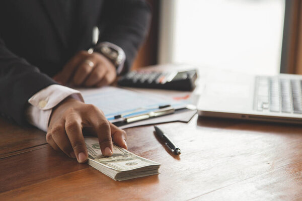 Close up of businessman with calculator counting money. in the company room.