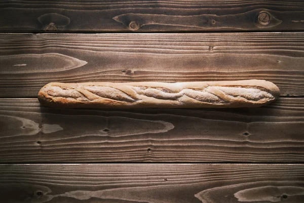 Tiro vertical de uma baguete francesa fresca em uma mesa de madeira. pronto para comer — Fotografia de Stock