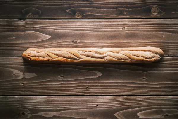 Вертикальний постріл свіжої французької багети на дерев'яному столі. готові їсти. — стокове фото