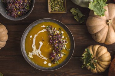 Ahşap arka planda balkabağı kremalı çorba. Yeşiller ve balkabakları. Faydalı bir beslenme ve öğle yemeği. Mesaj için yer. Düz yatış, üst görünüm