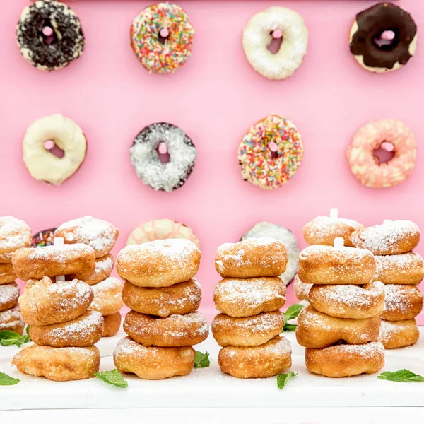 Donuts recién horneados en composición en la pared rosa . — Foto de Stock