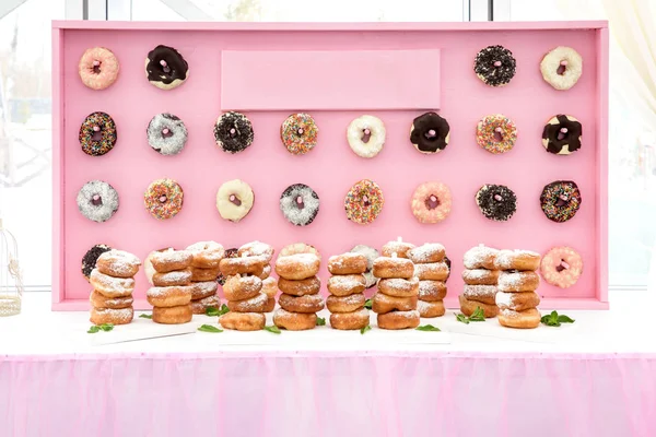 Donuts recién horneados en composición en la pared rosa . — Foto de Stock