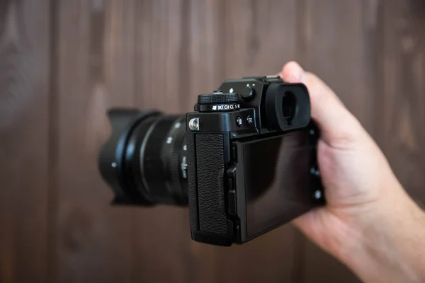 Hand halten und Aufnahme mit grünem Display spiegellose Kamera auf Holztisch — Stockfoto