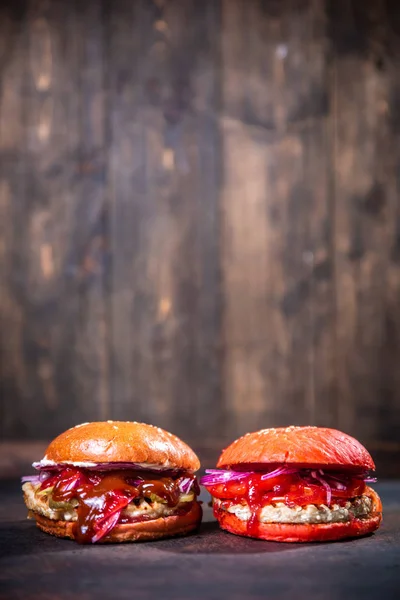 Fresco dos hamburguesas caseras en tablero de madera sobre fondo de madera oscura . — Foto de Stock