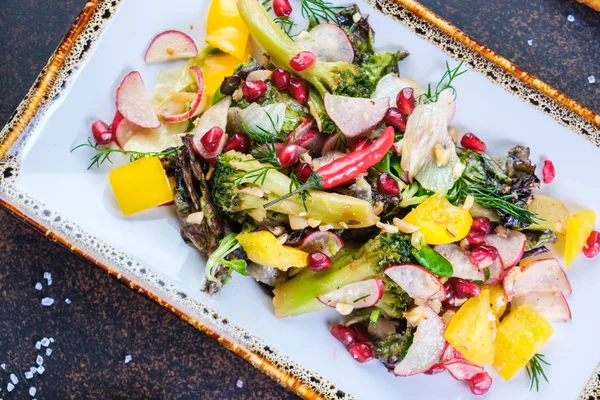 Ensalada saludable con espinacas, rúcula, cebolla roja y granada en plato sobre fondo de hormigón oscuro. Copiar espacio — Foto de Stock