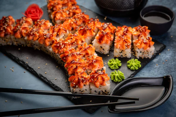 Set de sushi nigiri y rollos de sushi con té servido sobre pizarra de piedra gris sobre fondo metálico — Foto de Stock