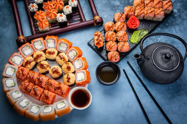 Set de sushi nigiri y rollos de sushi con té servido sobre pizarra de piedra gris sobre fondo metálico — Foto de Stock