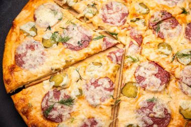 Salam, mozzarella ve turşu ile ev yapımı pizza. Koyu taş masada üst görünüm