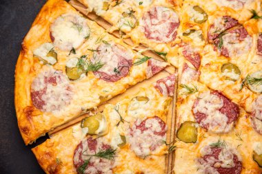 Salam, mozzarella ve turşu ile ev yapımı pizza. Koyu taş masada üst görünüm