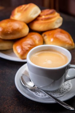 Kahve fincanı beyaz karanlık retro arka plan, seçici odak üzerinde ay çöreği. Kahvaltı konsepti