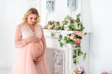 Güzel Pregant sarışın kadın ışık çalışmada karnını tutarak