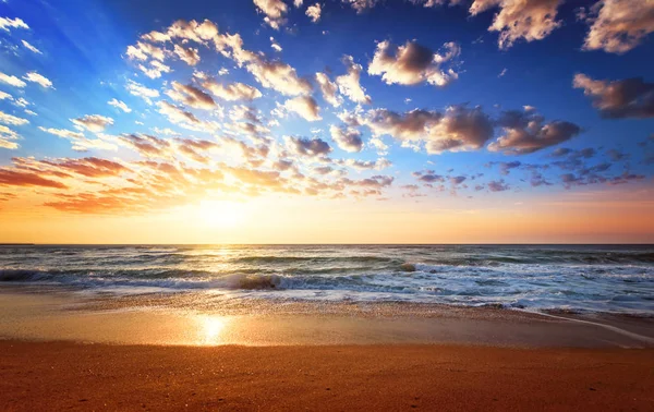 Sonnenuntergang Strand mit Wellen und bewölkt. — Stockfoto