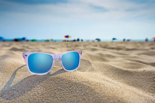 Sun glasses lie on a beach near the sea.