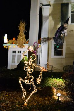 Cadılar Bayramı için bir Amerikan evinde süsleme. Ampullerden yapılmış bir iskelet, uçan bir cadı, oyulmuş balkabakları, bir korkuluk ve bir hayalet.