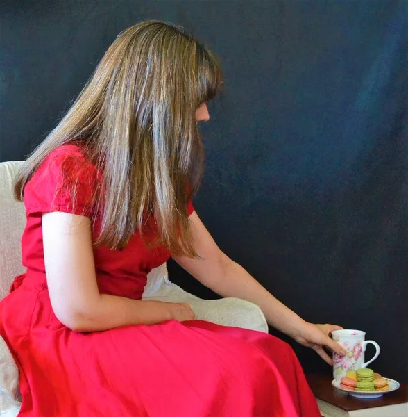 Mujer Sentada Vestido Rojo Sobre Fondo Negro Agarrando Una Taza —  Fotos de Stock