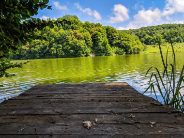Ahşap iskele veya İskelesi ve göl günbatımı ve gökyüzü su yansıma bir teknede.