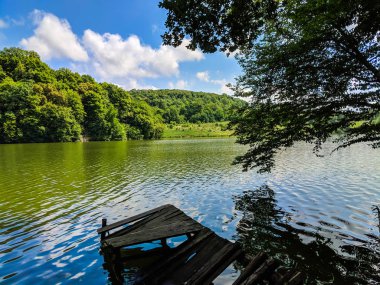 Ahşap iskele veya İskelesi ve göl günbatımı ve gökyüzü su yansıma bir teknede.