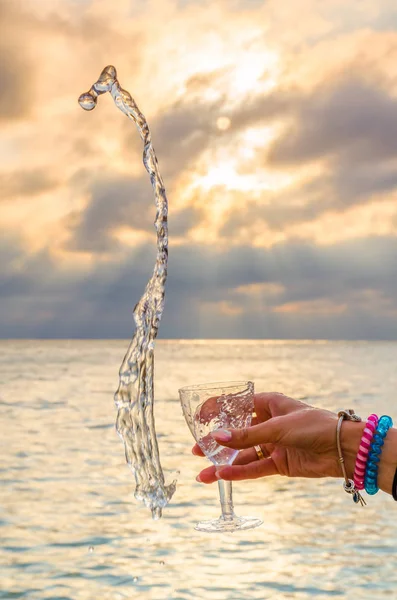 Chica Sosteniendo Una Copa Con Vino Vertiendo Atardecer Mar — Foto de Stock